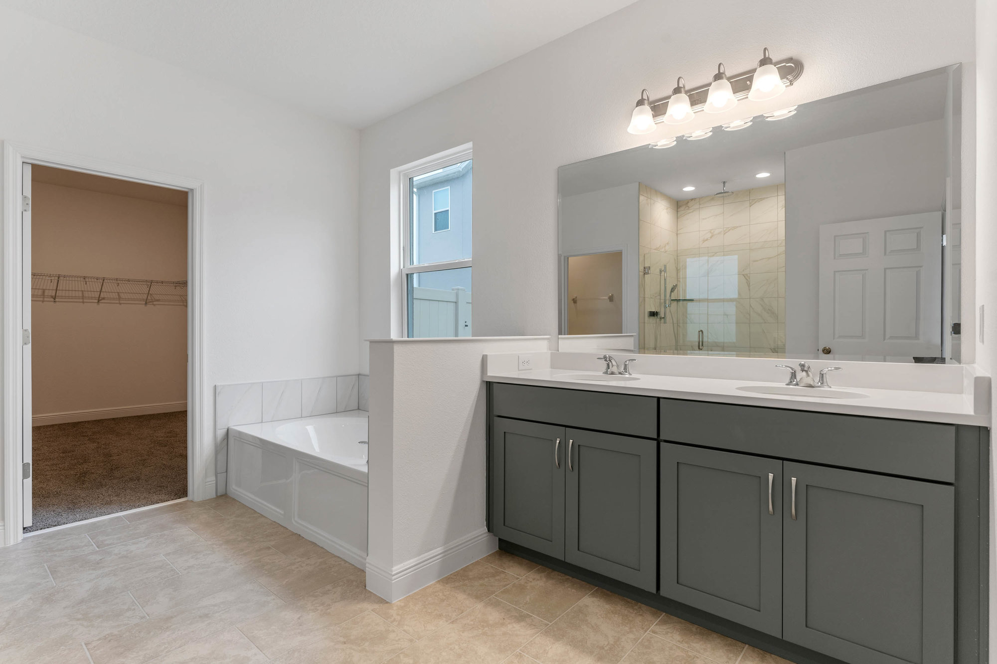bathroom with grey sink cabinet and white tub